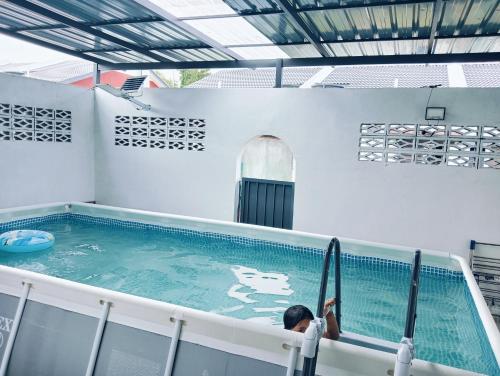 a person in a swimming pool with a surfboard at Santai Homestay PD in Port Dickson