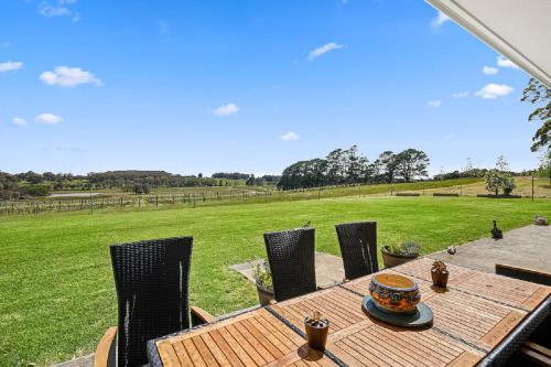 a wooden table and chairs with a view of a field at Exeter House Estate Vineyard Residence in Exeter