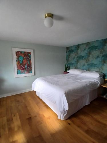 a bedroom with a white bed and a painting on the wall at Seaview in Stornoway