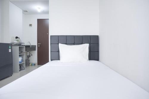 - une chambre avec un lit et un oreiller blanc dans l'établissement Cozy Living Studio Transpark Cibubur near Shopping Center Apartment By Travelio, à Depok