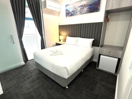 a bedroom with a white bed and a window at Palace Hotel Proserpine in Proserpine