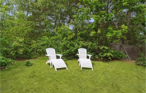 two white chairs sitting in the grass in a yard at Beautiful Home In Nexø With Wifi in Neksø