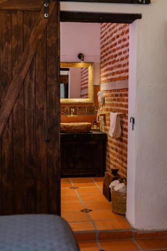 a bathroom with a wooden door and a mirror at Casa de hospedaje -La Abadía de San Pedro in Guadalajara