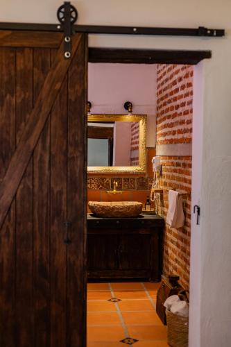a bathroom with a wooden door and a mirror at Casa de hospedaje -La Abadía de San Pedro in Guadalajara
