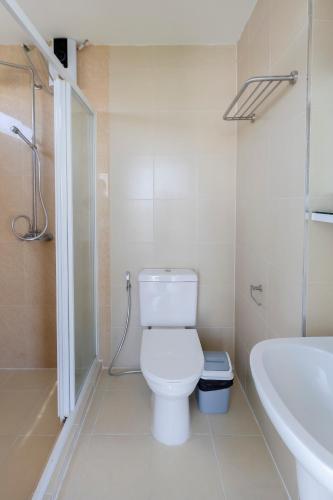 a white bathroom with a toilet and a sink at GP House Express Sukhumvit 81 in Bangkok