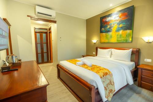 a bedroom with a large bed with a desk and a bed sidx sidx at The Central Lovina Hotel & Restaurant in Lovina
