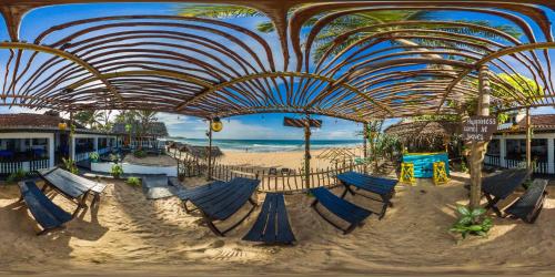a beach pavilion with blue chairs and a sandy beach at Sea Shine Guest House in Hikkaduwa
