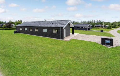 una casa negra en un campo de hierba con un edificio en 4 Bedroom Beautiful Home In Hemmet, en Hemmet