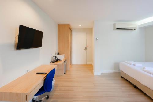a room with a desk and a bed and a tv at GP House Express Sukhumvit 81 in Bangkok