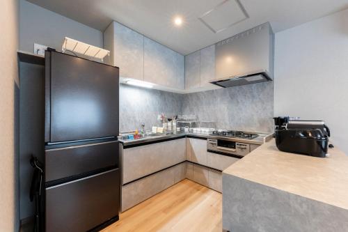 a kitchen with a black refrigerator and a counter at The Comfy Sapporo in Ōdōri