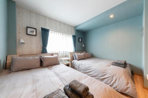 two beds in a room with blue walls at The Comfy Sapporo in Ōdōri