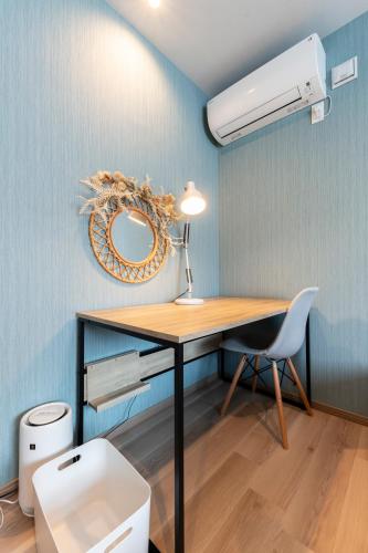 a desk with a lamp and a fan in a room at The Comfy Sapporo in Ōdōri