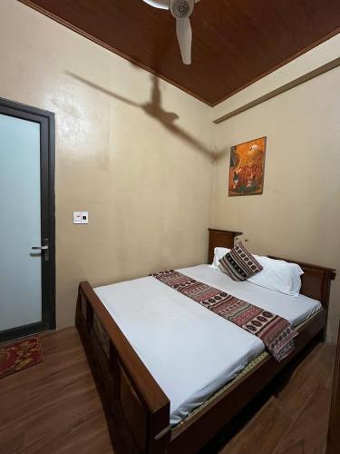 a bedroom with a bed with white sheets and a ceiling at Homestay Cánh Đồng Vàng in Hữu Lũng