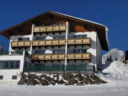 a building with a balcony on top of snow at Aparthotel Sunrise in Ramsau am Dachstein