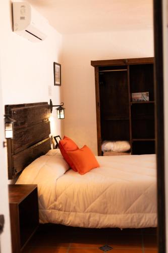 a bedroom with a bed with an orange pillow on it at Casa de hospedaje -La Abadía de San Pedro in Guadalajara