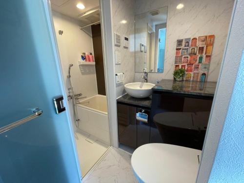 a bathroom with a toilet and a sink and a tub at COMMA HOUSE Shinjuku 401 in Tokyo