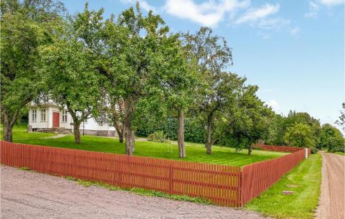 a red fence in front of a yard with trees at 4 Bedroom Stunning Home In Ödeshög in Ödeshög