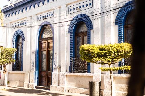 a white building with blue arches and doors at Casa de hospedaje -La Abadía de San Pedro in Guadalajara