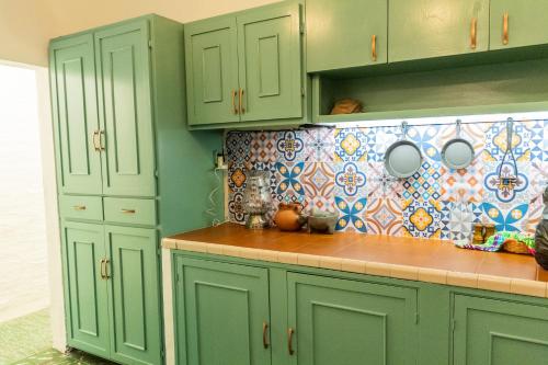 a kitchen with green cabinets and a tile wall at Casa de hospedaje -La Abadía de San Pedro in Guadalajara