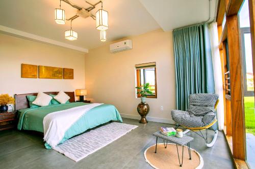 a bedroom with a green bed and a chair at Laluka House in Hoi An