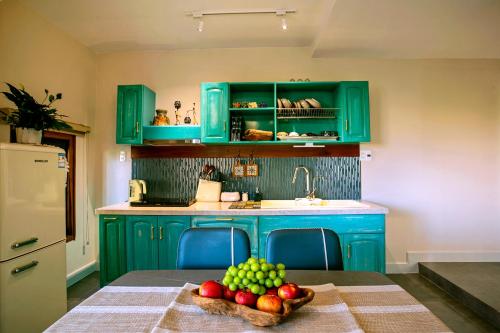 a kitchen with green cabinets and a table with a bowl of fruit at Laluka House in Hoi An