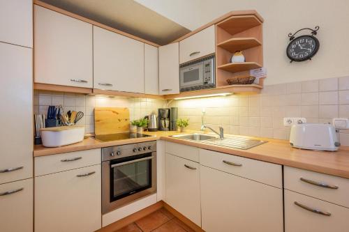 a kitchen with white cabinets and a sink and a clock at Südwind 06 in Zempin