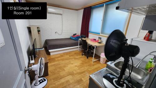 a small room with a bed and a desk and a kitchen at Daejeon Guesthouse Sky Garden in Daejeon