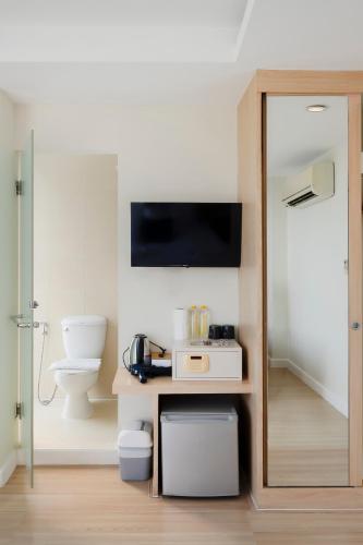 a bathroom with a toilet and a tv on the wall at GP House Express Sukhumvit 81 in Bangkok