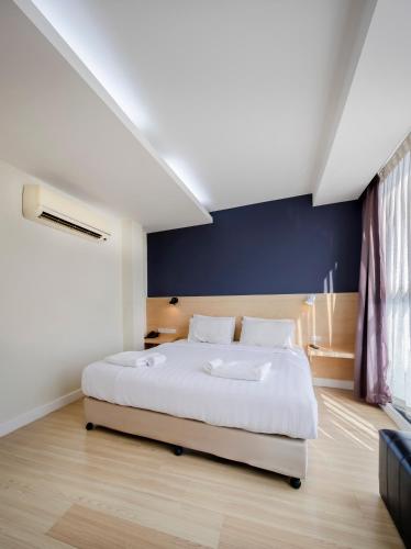 a bedroom with a white bed and a blue wall at GP House Express Sukhumvit 81 in Bangkok