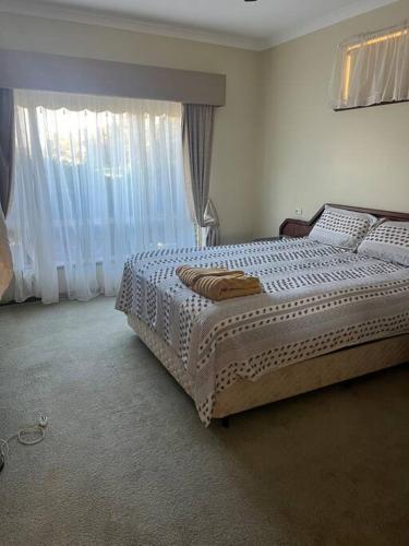a bedroom with a bed with white sheets and windows at Myra Downs in Harvey