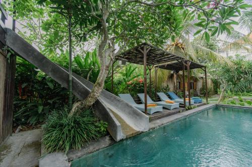 a swimming pool with lounge chairs next to a house at The Onion Collective in Ubud