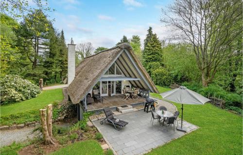 a thatch roofed house with a patio and umbrella at 2 Bedroom Nice Home In Aabenraa in Loddenhøj