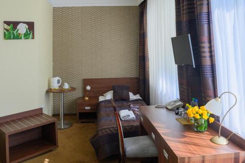 a hotel room with a bed and a desk with a television at Hotel & SPA Odeon in Boguchwała