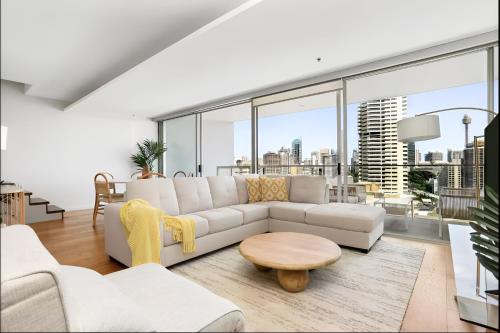 a living room with a white couch and a table at Stylish Double Storey Apt plus Harbour Bridge Views! in Sydney