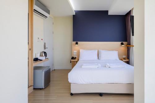 a bedroom with a white bed and a blue wall at GP House Express Sukhumvit 81 in Bangkok