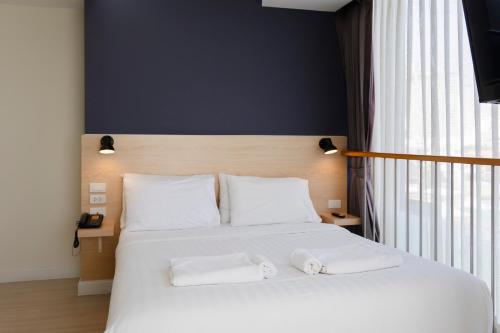 a bedroom with a white bed with two towels on it at GP House Express Sukhumvit 81 in Bangkok