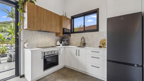eine Küche mit weißen Schränken und einem schwarzen Kühlschrank in der Unterkunft Catalyst Retreat - Stylish, Pets, Accessible, Sauna in Coffs Harbour