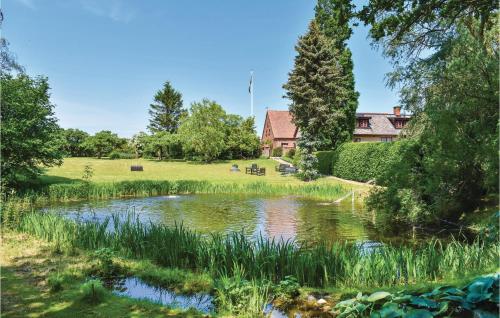 a pond in a park with a house in the background at Lindersgården in Staffanstorp