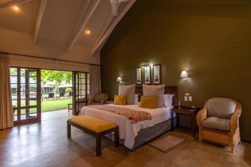 a bedroom with a king sized bed and a chair at Perry's Bridge Hollow Boutique Hotel in Hazyview