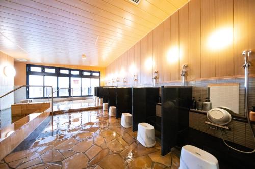 a large bathroom with a row of urinals and toilets at Akarinoyado Togetsu in Beppu