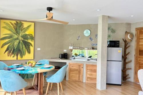 a kitchen with a table and blue chairs and a refrigerator at Villa Cefloralie - A Tranquil Retreat in Koh Samui in Koh Samui