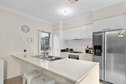 a white kitchen with a sink and a refrigerator at Cosy 5 x bedroom Kellyvil Ridge in Kellyville