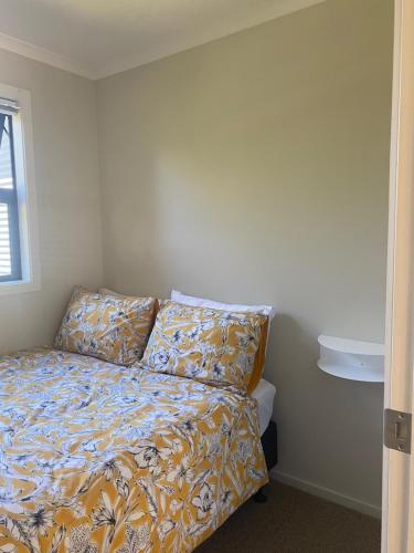 a bedroom with a bed with a bedspread and a window at Kurow Garden Retreat in Kurow