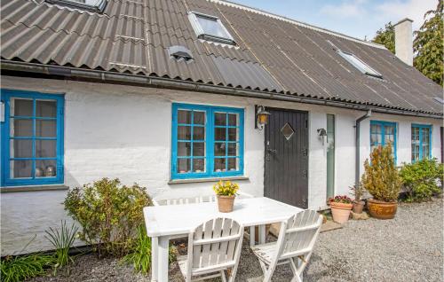 a white house with blue windows and a white table and chairs at Gorgeous Apartment In Gudhjem With Wifi in Gudhjem