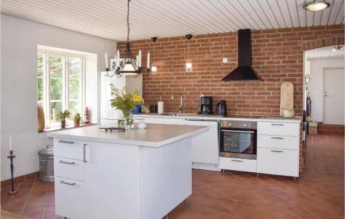a kitchen with white cabinets and a brick wall at Cozy Home In Gärsnäs With Wifi in Gärsnäs