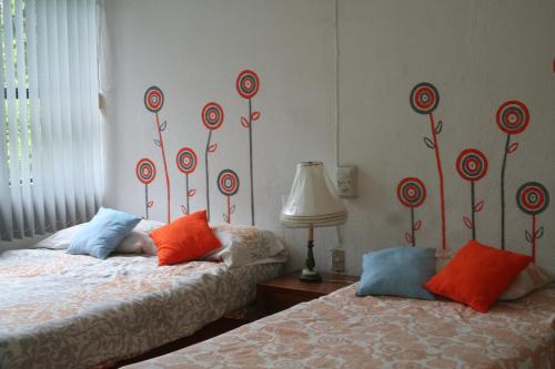 2 camas en una habitación con almohadas rojas y azules en Casa Laguna Magica, en Catemaco