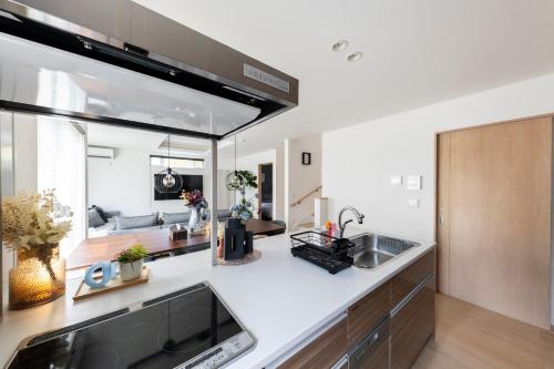 a kitchen with white countertops and a living room at The Verite in Asahikawa