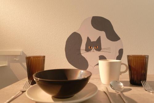 a black and white cat on a table with a cup at Gaia BOSCO by Tranova in Tokyo