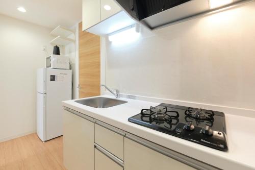 a kitchen with a stove and a sink and a refrigerator at Gaia BOSCO by Tranova in Tokyo