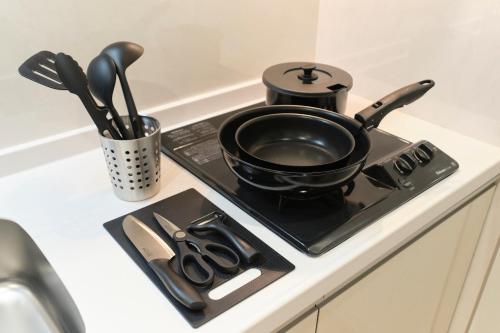 a black pot sitting on a stove with scissors at Gaia BOSCO by Tranova in Tokyo